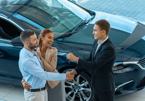 Happy beautiful couple is choosing rental car at dealership for traveling